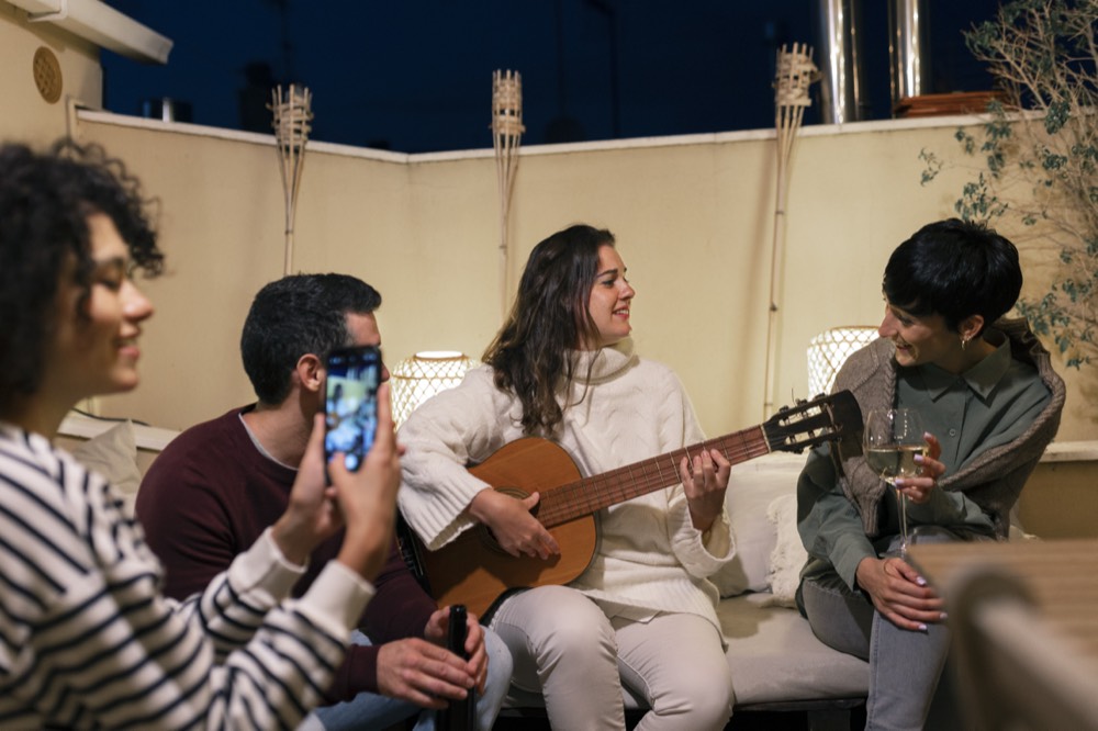 Friends sitting close together listening to someone play guitar