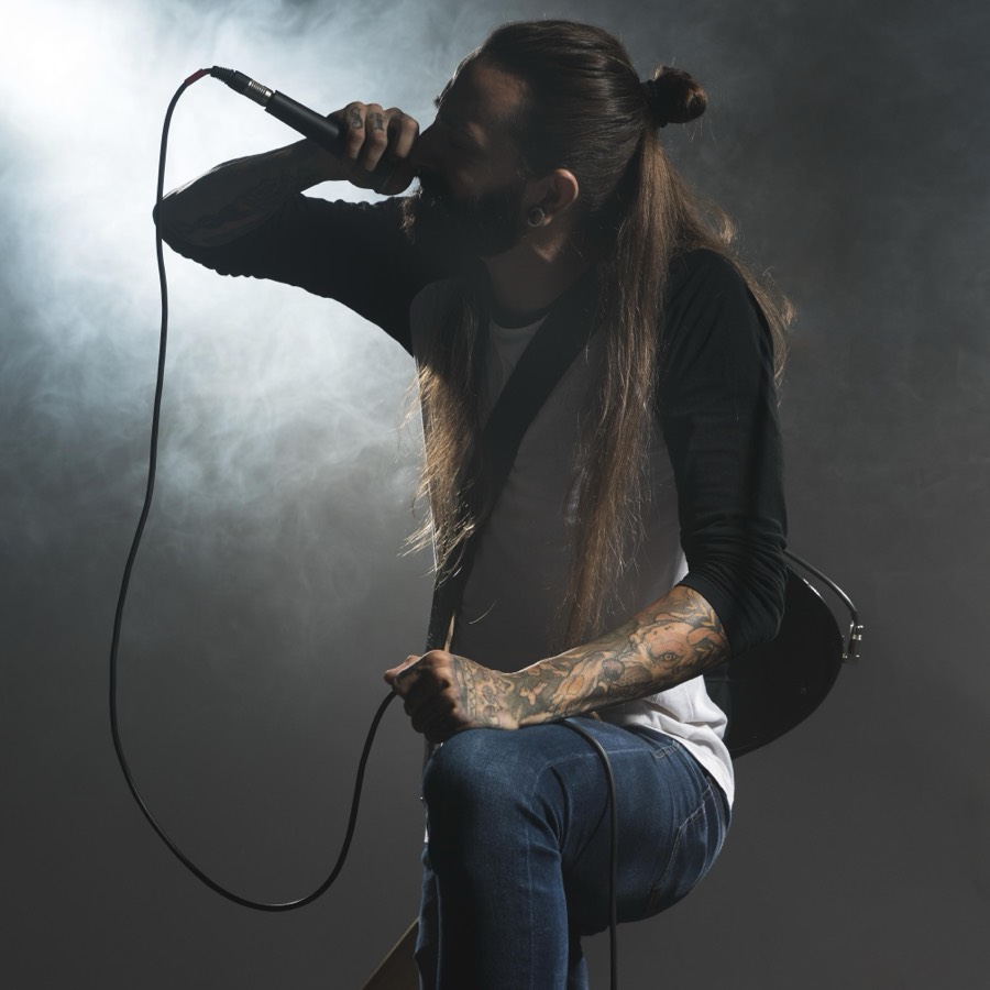 A singer performing into a microphone under stage haze